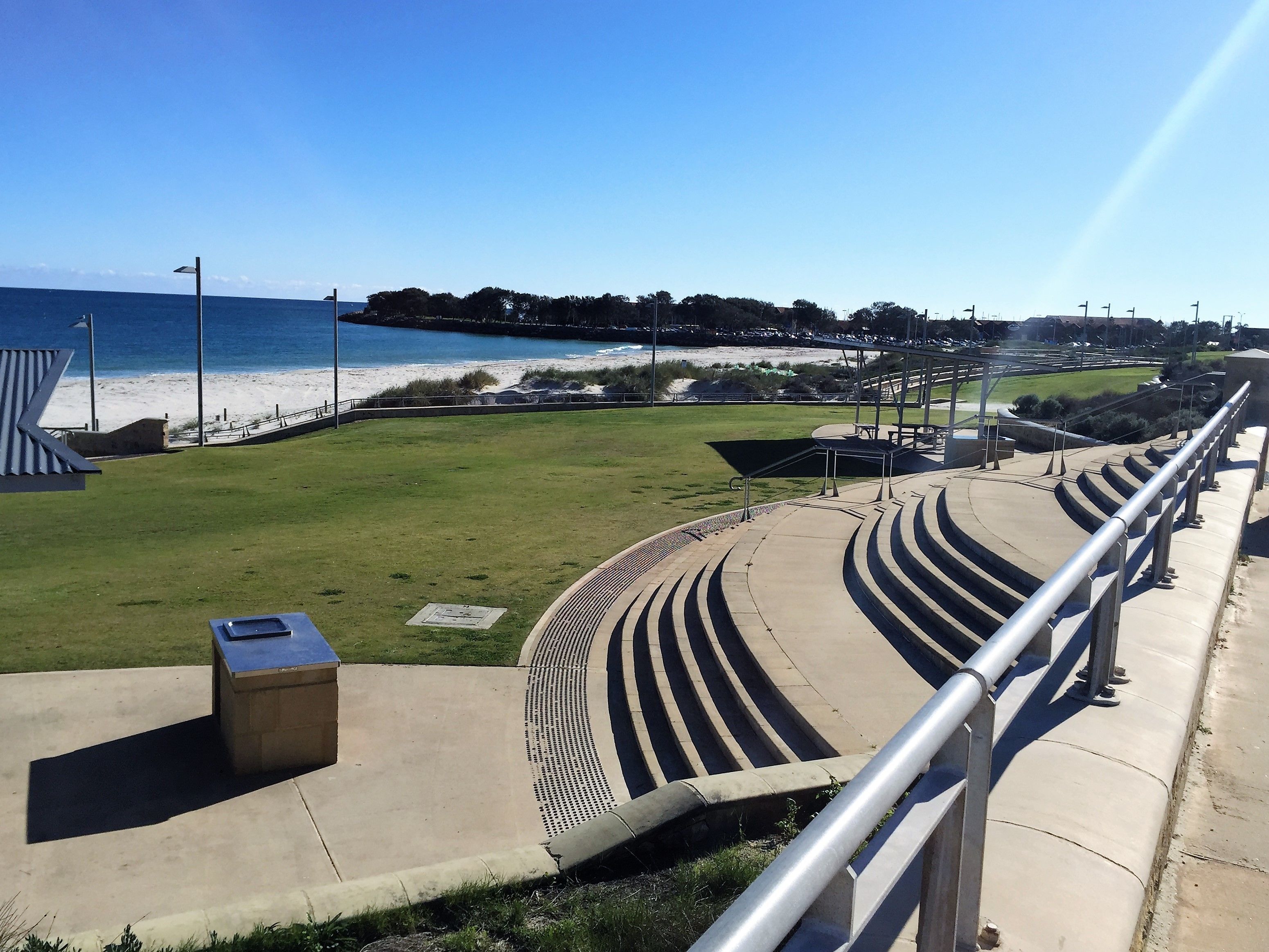 A stadium with tiered seating, a grassy area, and a beach in the background.