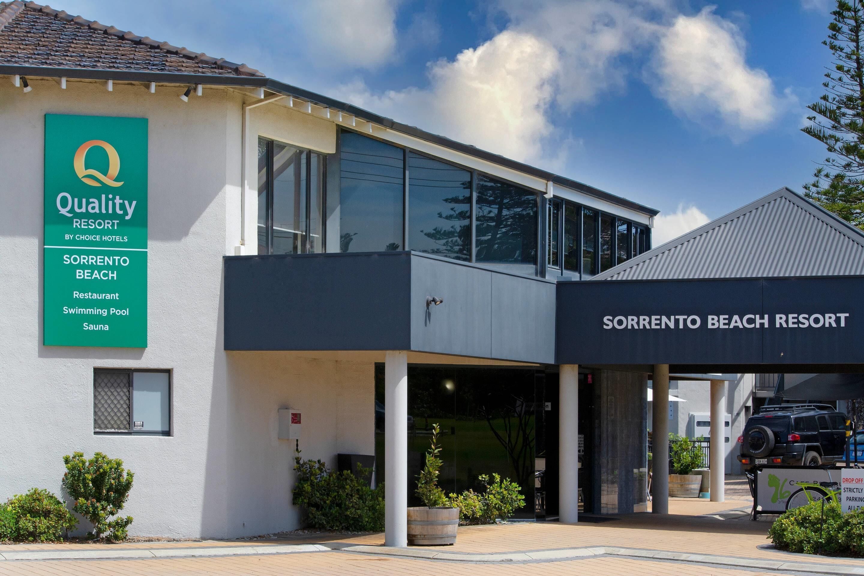 A modern building with a sign for 'Quality Resort by Choice Hotels' and 'Sorrento Beach Resort'.