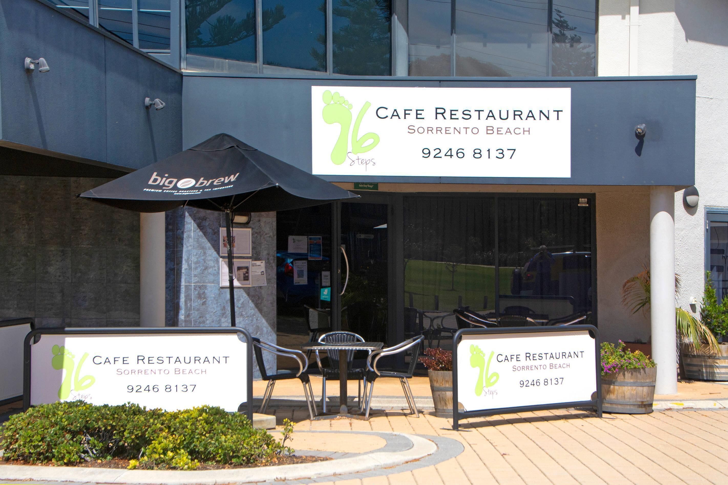 A cafe restaurant with outdoor seating, a black umbrella, and a sign with the cafe's name and phone number.