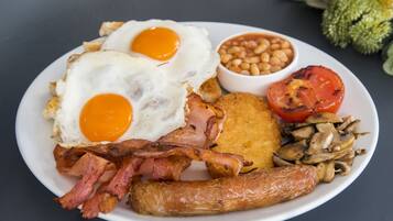 Un plato de comida para el desayuno con huevos, tocino, salchichas, champiñones, frijoles y tomate a la parrilla.