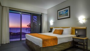 Una habitación de hotel con una cama grande, una mesita de noche, una lámpara y un cuadro en la pared.