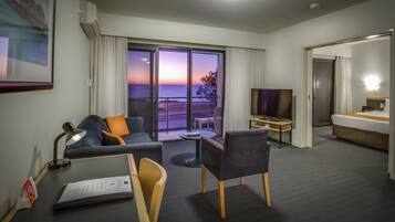 Una habitación de hotel con balcón, televisión, escritorio y cama.