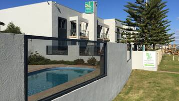 A modern building with a swimming pool, a cafe restaurant sign, and a flag.