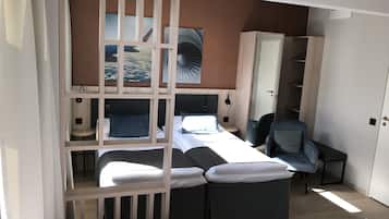 A compact bedroom with a bunk bed, a single bed, a desk, and a chair.