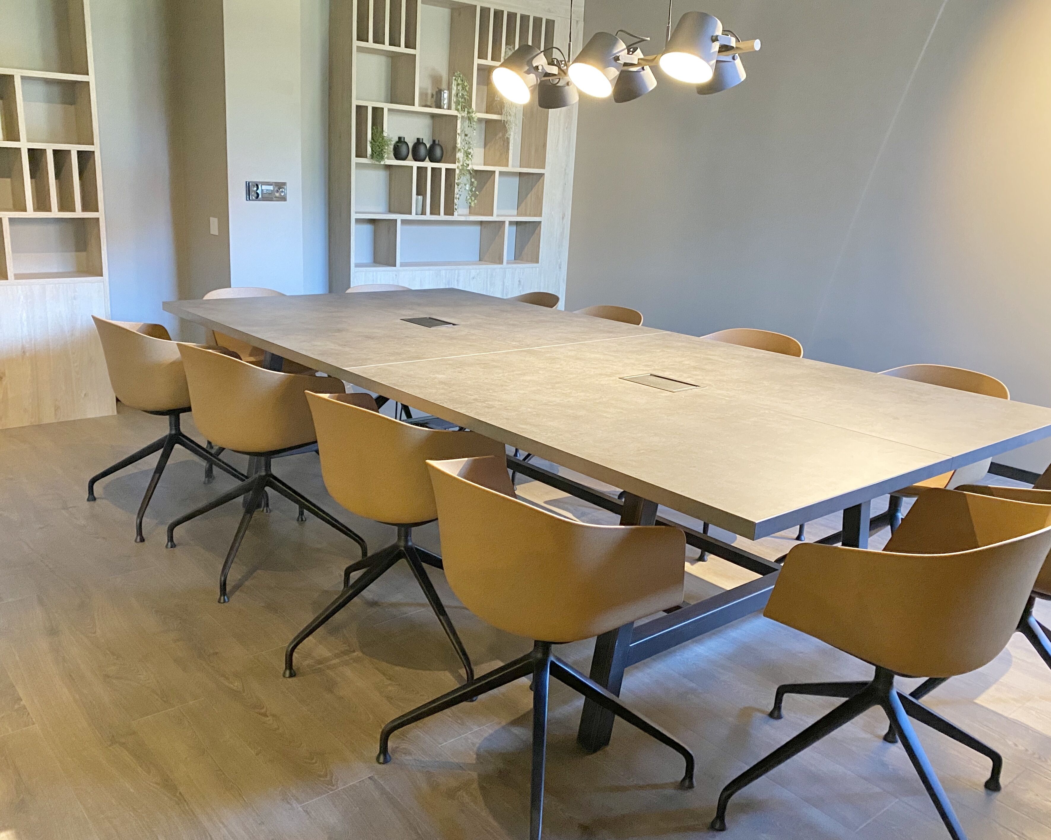 A conference room with a long table, six chairs, and a ceiling light fixture.
