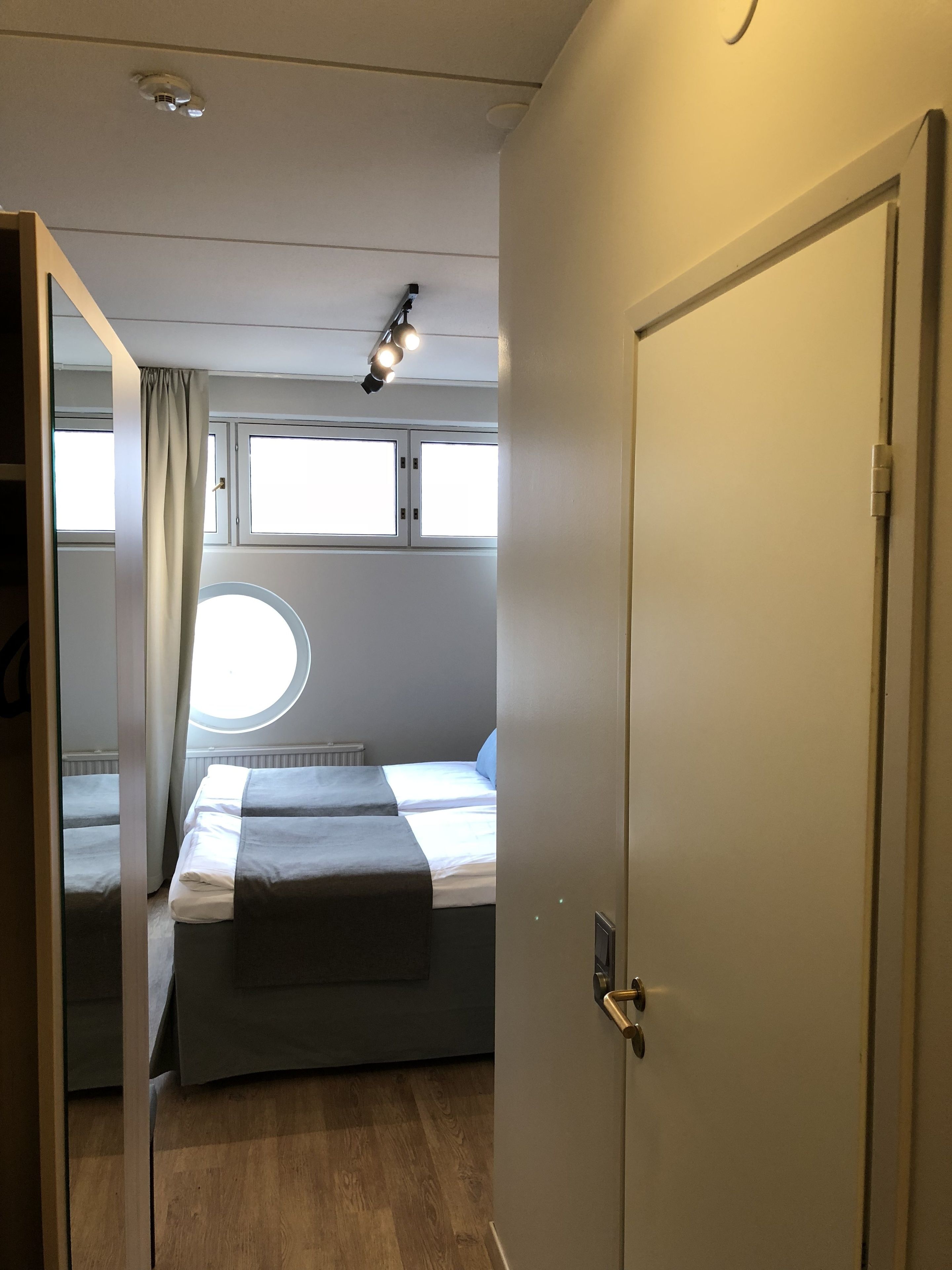 A bedroom with two beds, a window, and a door.