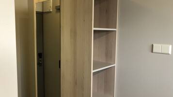 A room with a wooden wardrobe, a door, and a light switch on the wall.