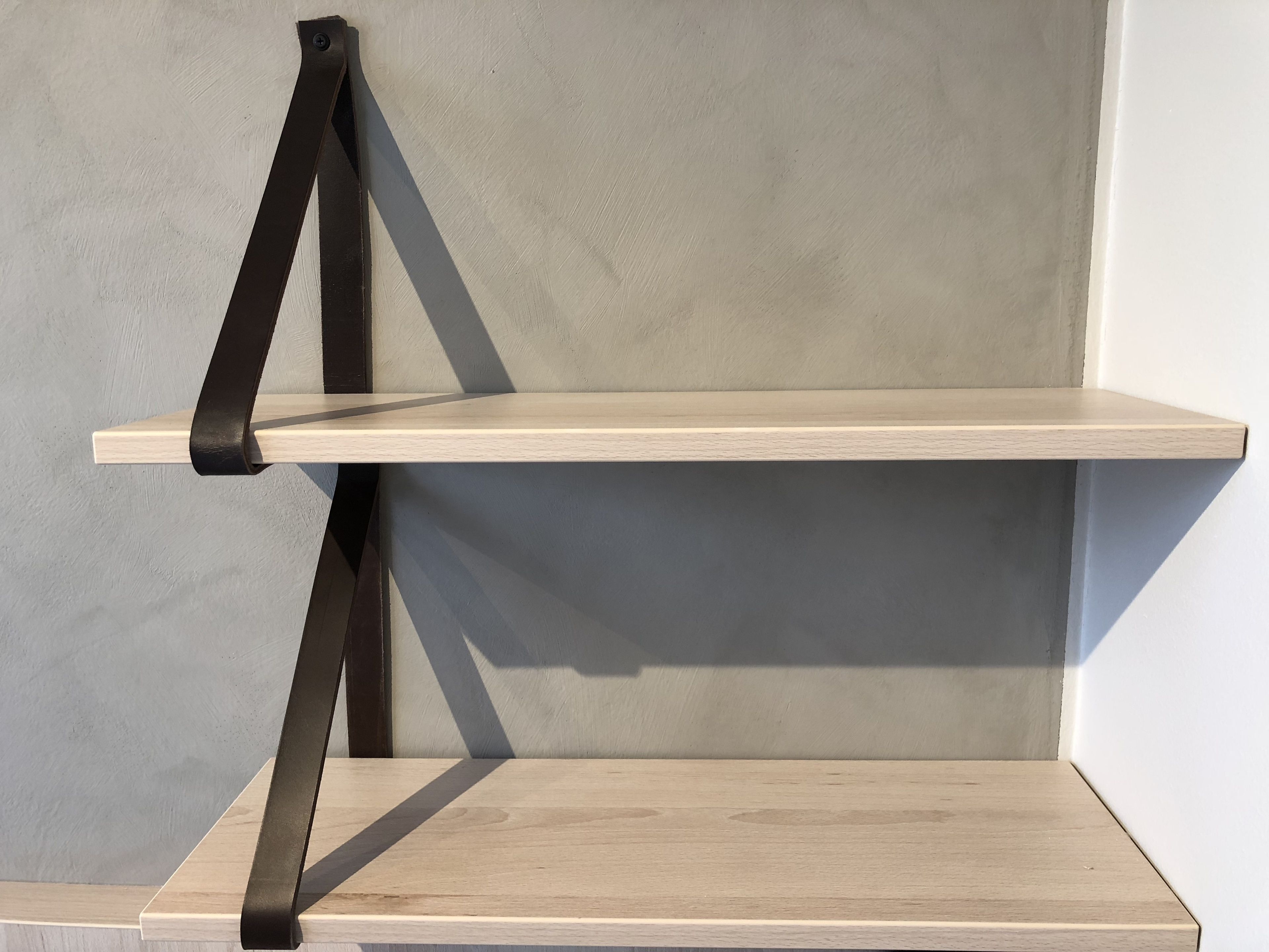 A minimalist shelf unit with a single shelf against a plain wall.