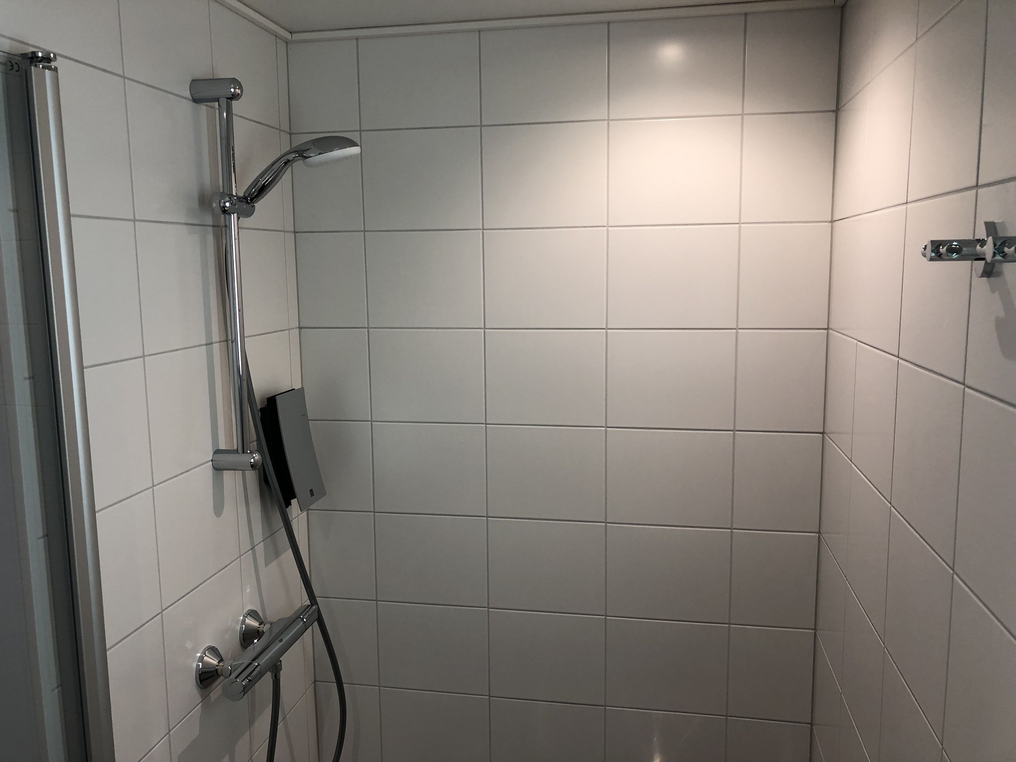 Um chuveiro com chuveiro manual e painel de controle fixado na parede.