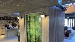 Un área de bar moderna con mostrador de madera, taburetes y un ventanal con vistas al bosque.