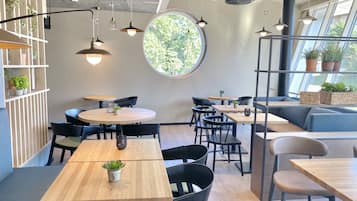 Un caffè moderno con tavoli rotondi, sedie nere e pavimento in legno.