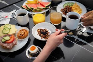A breakfast table with plates of food, drinks, and utensils.