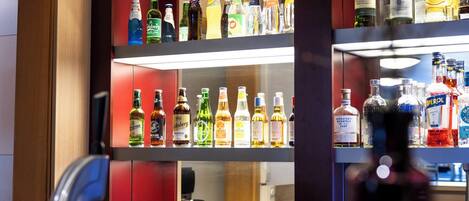 Zona de bar con estantes llenos de botellas de licores y vasos.