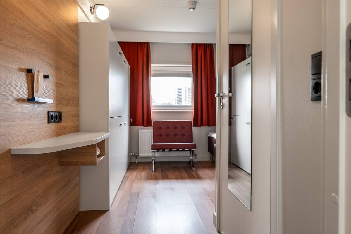 Ett modernt kök med träinredning, en inbyggd bänk och ett fönster med röda gardiner.