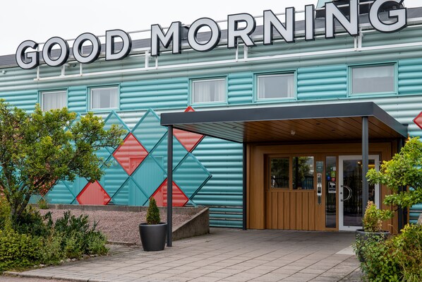 A building with a sign that reads "GOOD MORNING" and a modern entrance with a covered walkway.