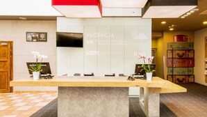 A reception desk with a flat-screen TV, a welcome sign, and a wall-mounted information board. - ibis Lodz Centrum (Lodz)