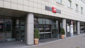 The exterior of an ibis hotel with large glass doors, potted plants, and a sign indicating the hotel's name. - ibis Lodz Centrum (Lodz)