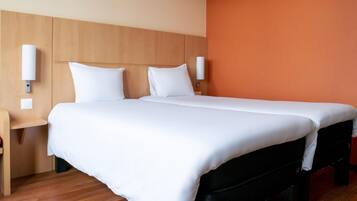 Una habitación de hotel con una cama grande, cabecera de madera, dos mesitas de noche y una lámpara de pared.