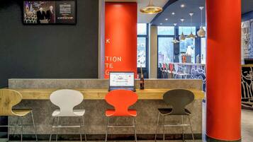 A reception area with a counter, three chairs, a laptop, and a wall-mounted screen.