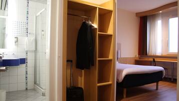 Een hotelkamer met een douche, een bed, een bureau en een kledingkast.