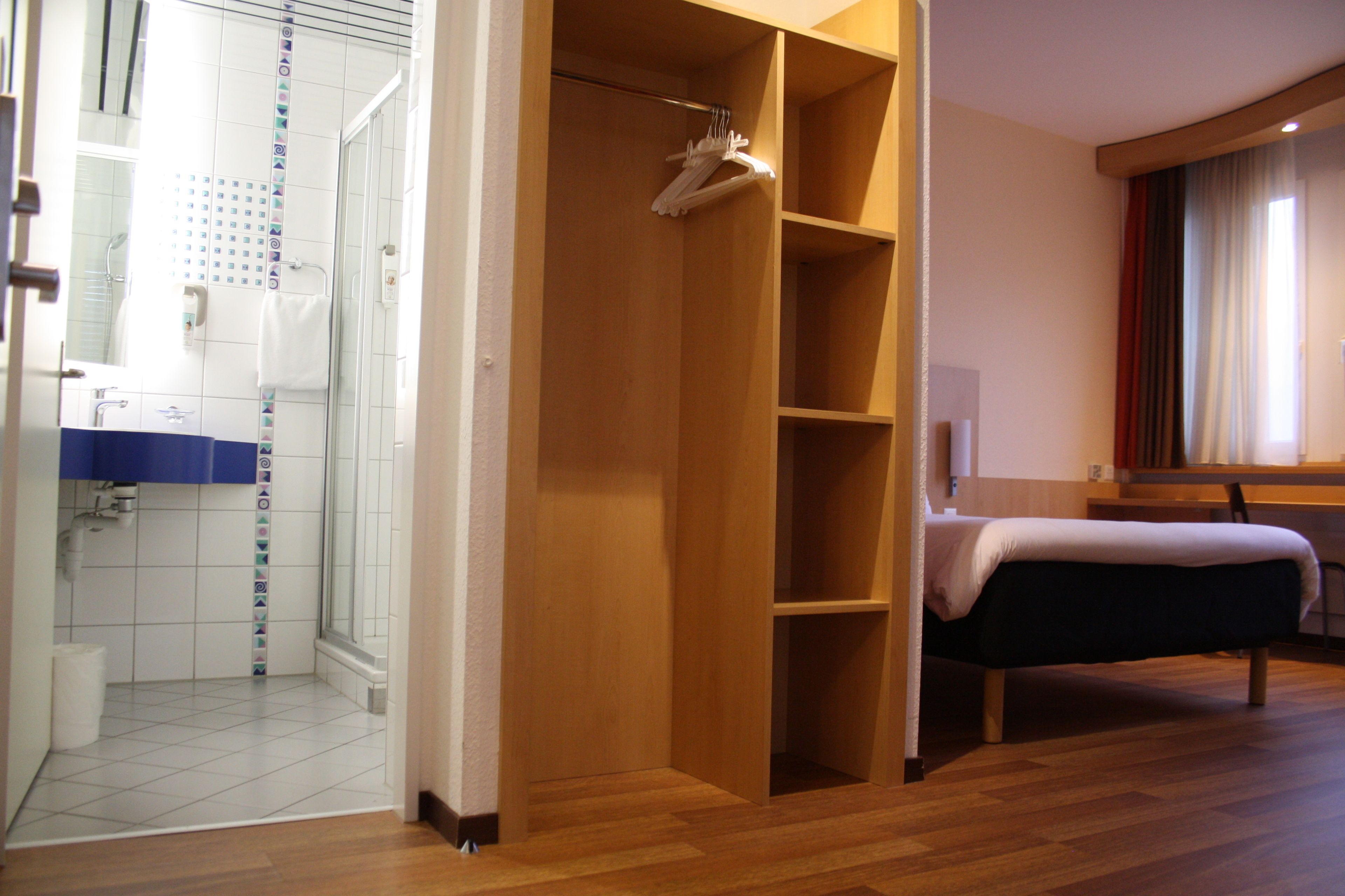 Une chambre d’hôtel avec une douche, un lit et une armoire en bois.
