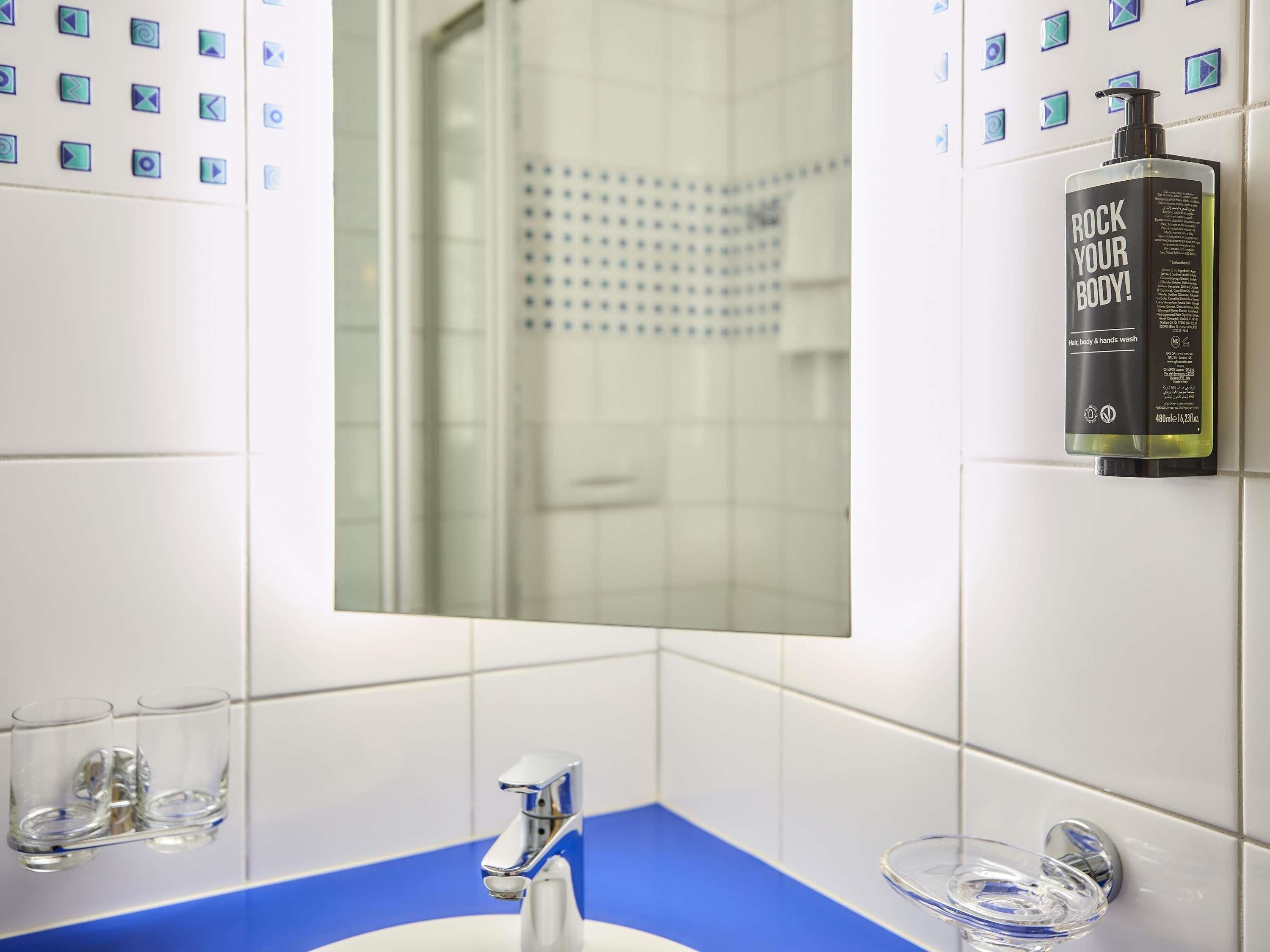 Une salle de bain avec un miroir, un lavabo et un espace douche.