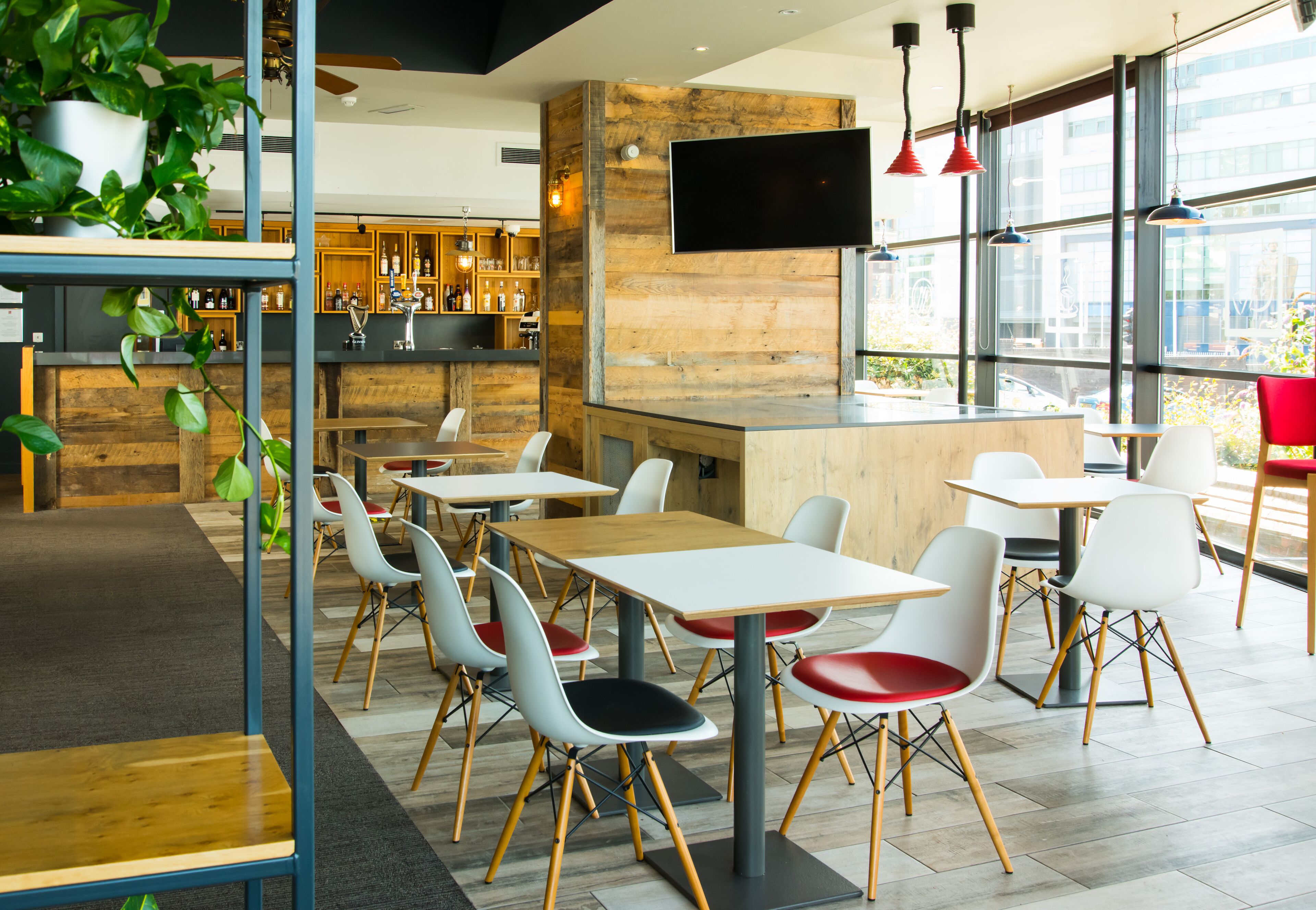 A modern cafe with a bar area, seating, and large windows.