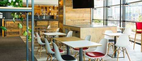 A modern cafe with a bar area, seating, and large windows.