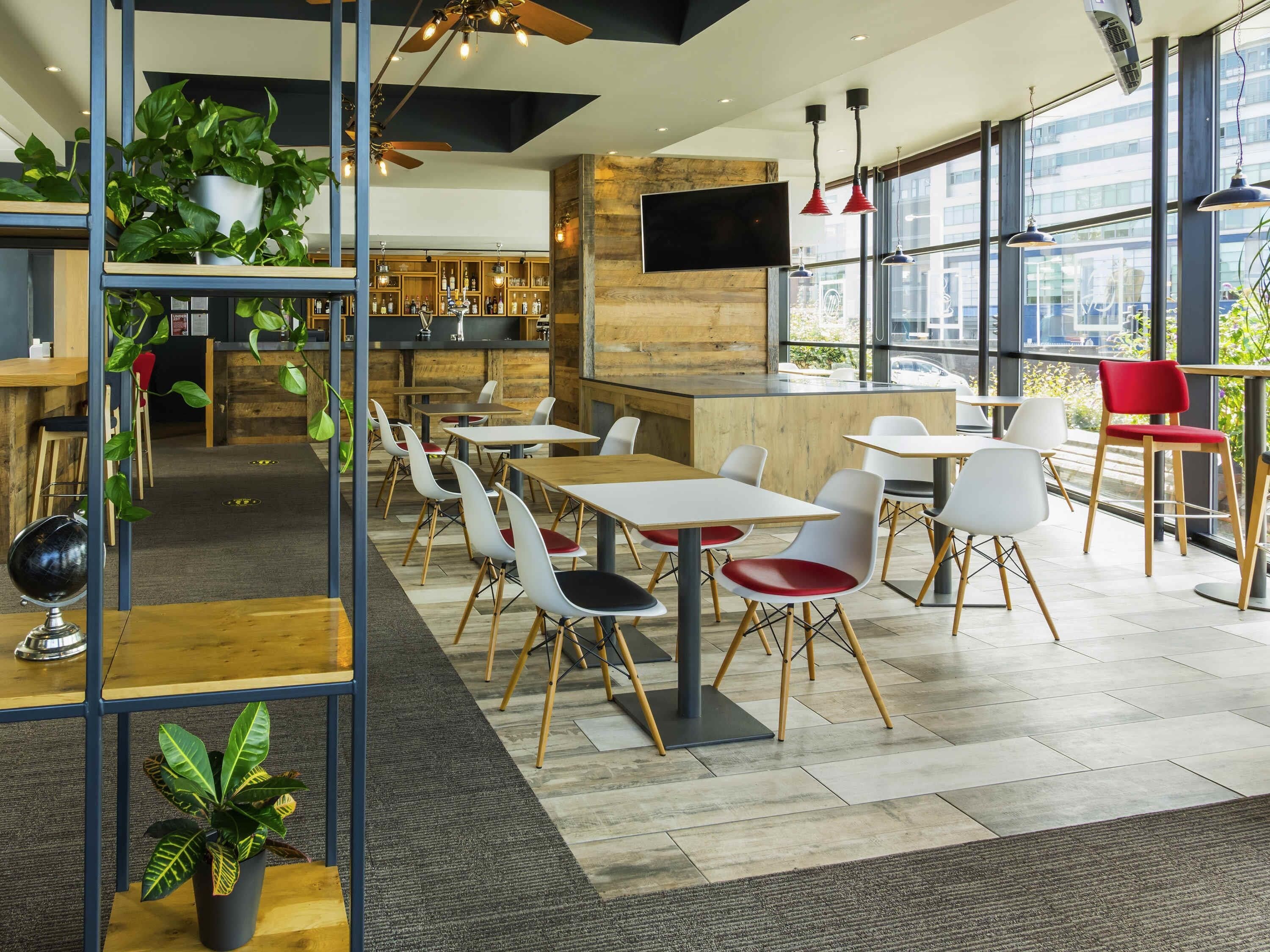 Een modern restaurantinterieur met tafels, stoelen, een bar en grote ramen.