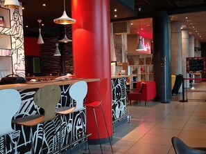 A modern interior with a bar area, red and black decor, and seating. - ibis Warszawa Centrum (Warsaw)