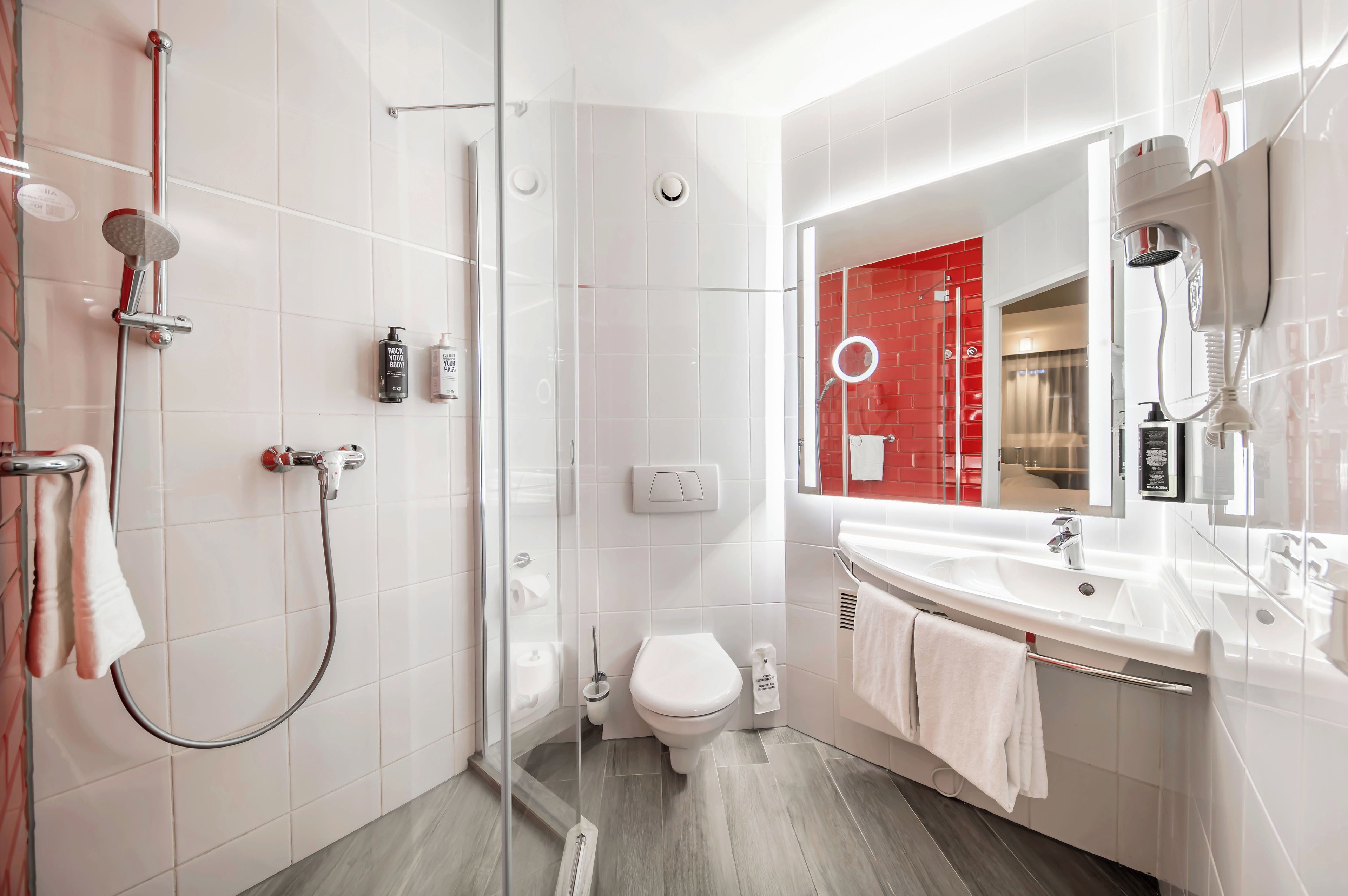 Une salle de bain moderne avec une douche à parois de verre, des toilettes et un lavabo avec un miroir.