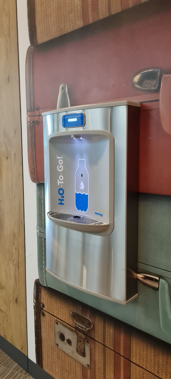 A water dispenser with a label that reads "H2O To-Go!" mounted on a suitcase. - ibis Warszawa Centrum (Warsaw)