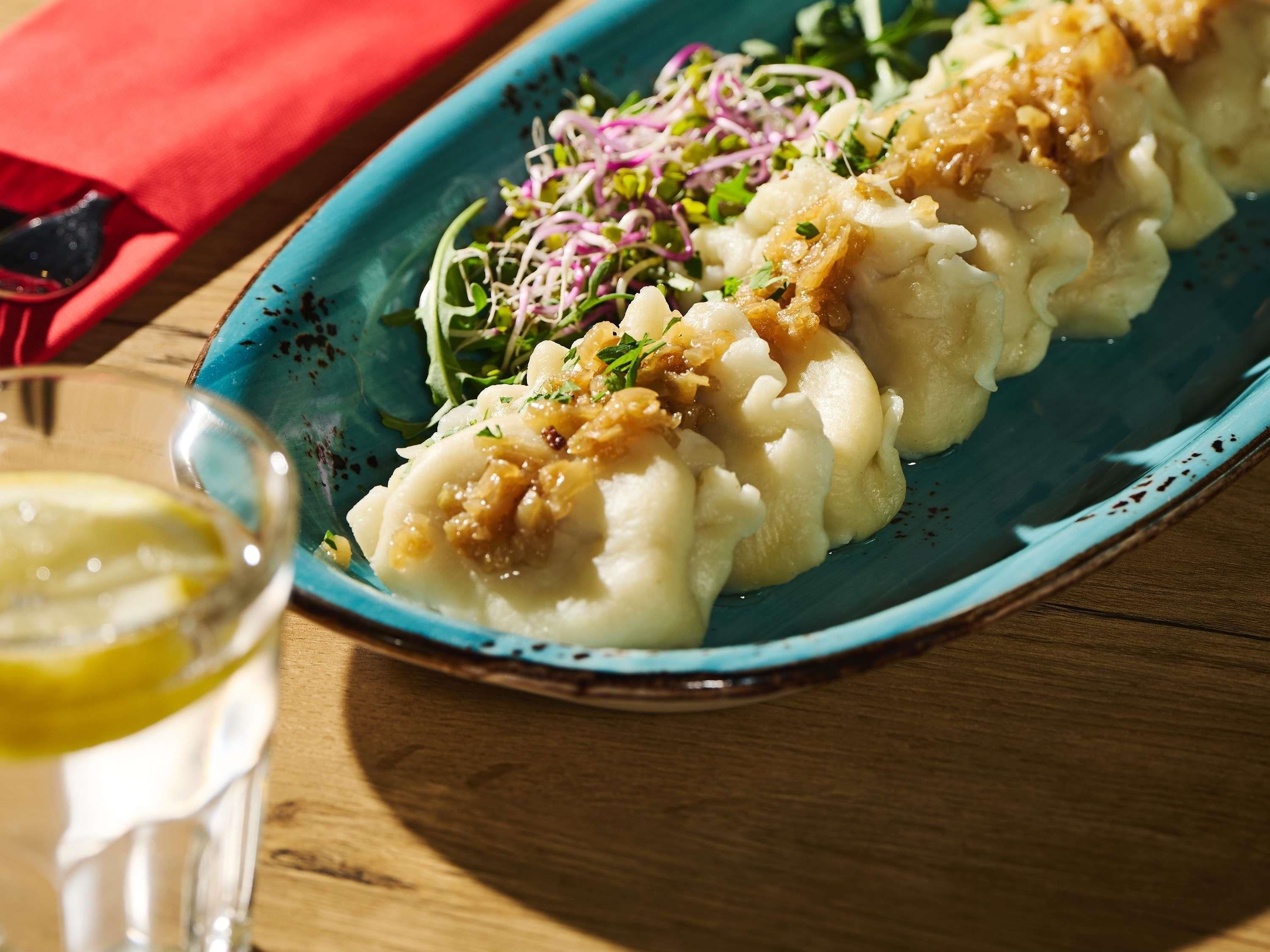 A plate of food with a side of salad and a glass of drink on a wooden table.