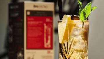 A glass with a straw, lemon slice, mint, and cinnamon stick, with a box in the background.