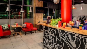 Et moderne restaurantinteriør med røde siddepladser, en trædisk og hængende lamper.