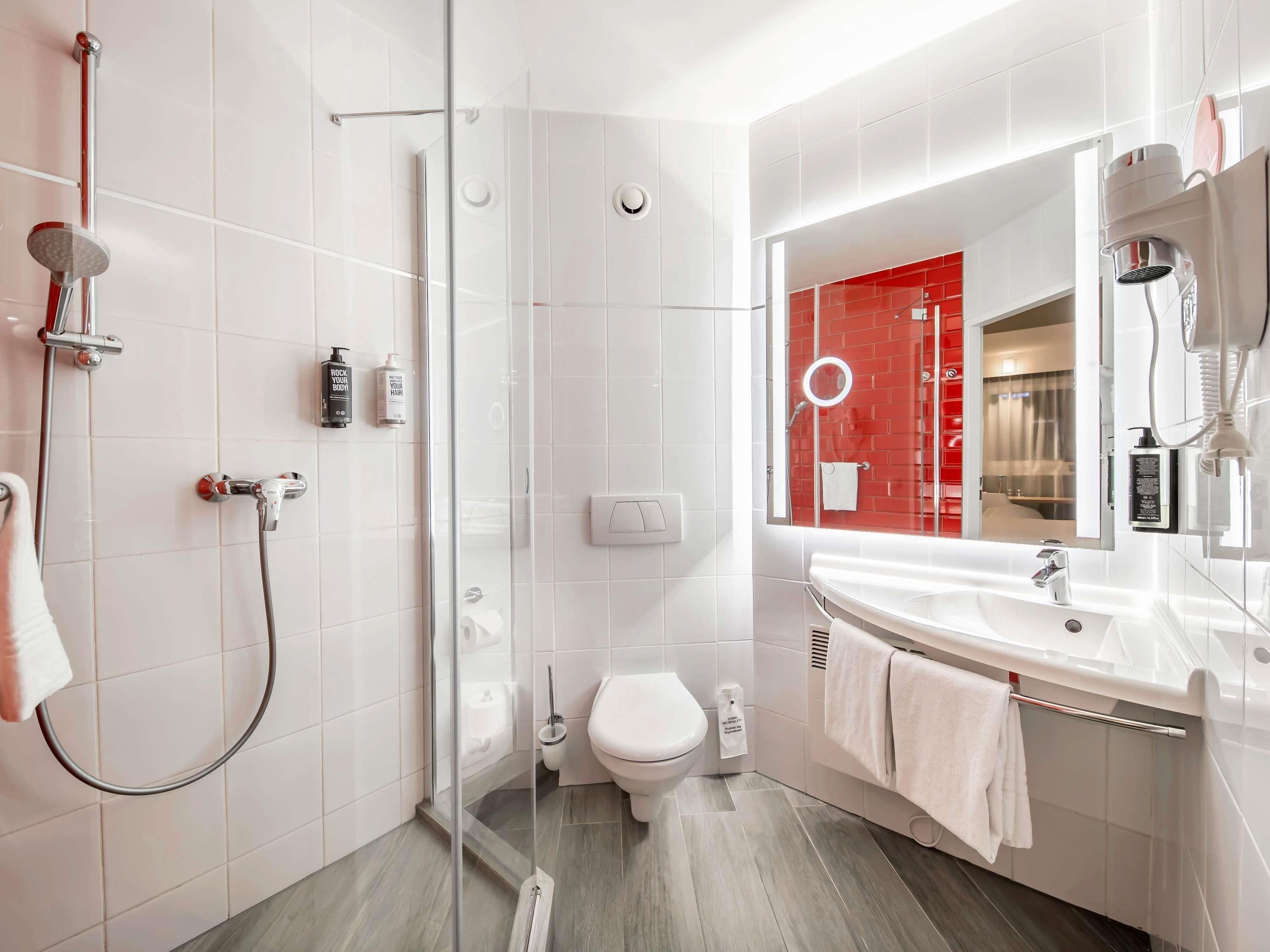 A modern bathroom with a glass-enclosed shower, a white toilet, and a vanity with a mirror.