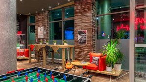 A modern indoor space with a foosball table, seating area, and a wall with a poster. - ibis Warszawa Centrum (Warsaw)