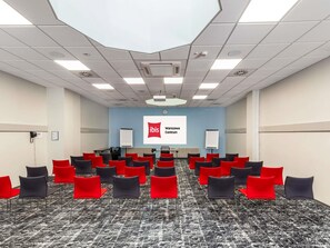 A conference room with a carpeted floor, rows of chairs, a projector screen, and a whiteboard. - ibis Warszawa Centrum (Warsaw)