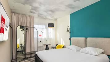 Habitación de hotel con cama, escritorio, silla, lámpara y vista a la ciudad.