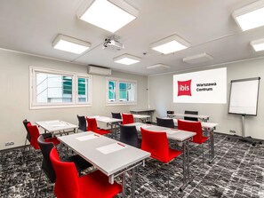 A conference room with tables, chairs, a projector screen, and a whiteboard. - ibis Warszawa Centrum (Warsaw)