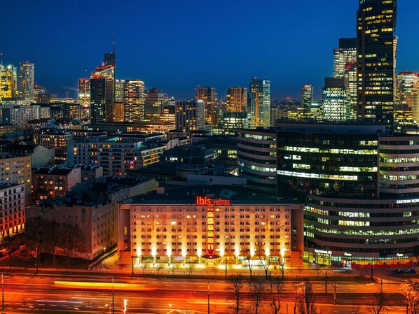 A cityscape with a prominent hotel building labeled 'ibis HOTEL' in the foreground, surrounded by high-rise buildings. - ibis Warszawa Centrum (Warsaw)