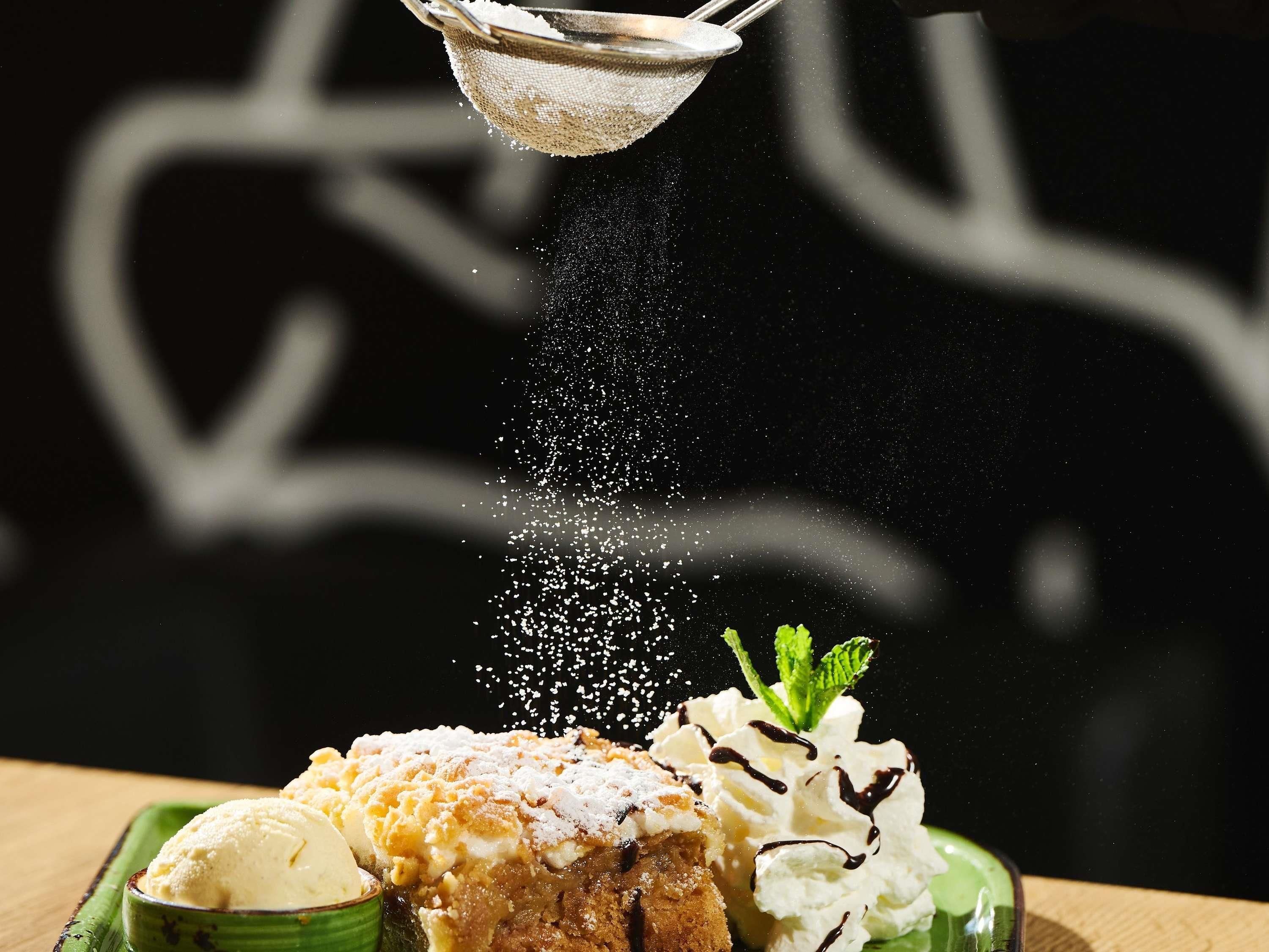 A dessert with whipped cream and a mint garnish, dusted with powdered sugar.