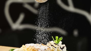 A dessert with whipped cream and a mint garnish, dusted with powdered sugar.