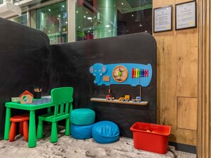 A children's play area with a train set, green chairs, and a small house model. - ibis Warszawa Centrum (Warsaw)