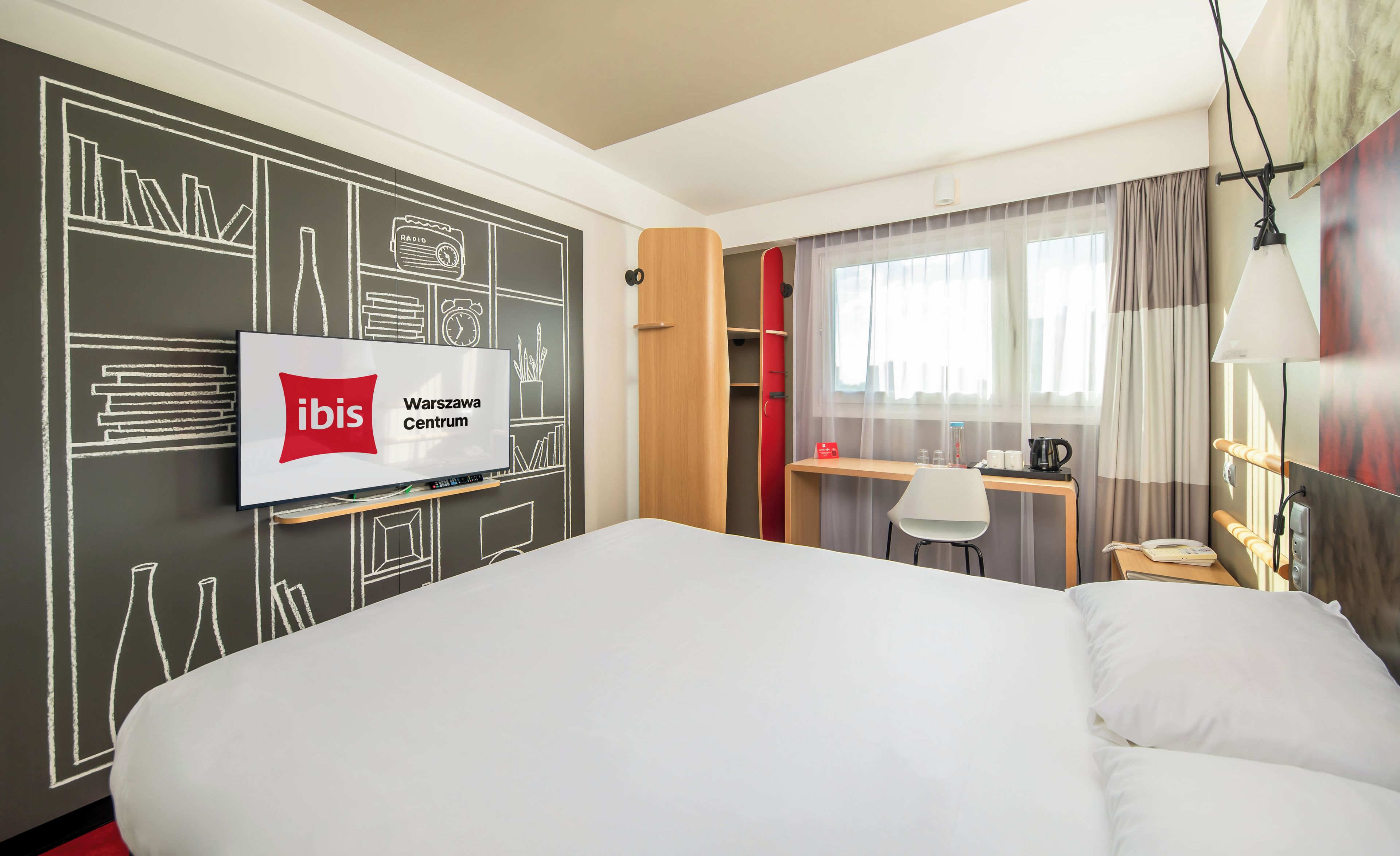 Una habitación de hotel con una cama, un escritorio, una silla, un televisor y un armario.