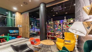 Et moderne interiør med en træreception, farverige stole, en reol og en stor søjle.