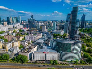 A modern cityscape with a prominent hotel featuring a curved facade and a flat roof. - ibis Warszawa Centrum (Warsaw)
