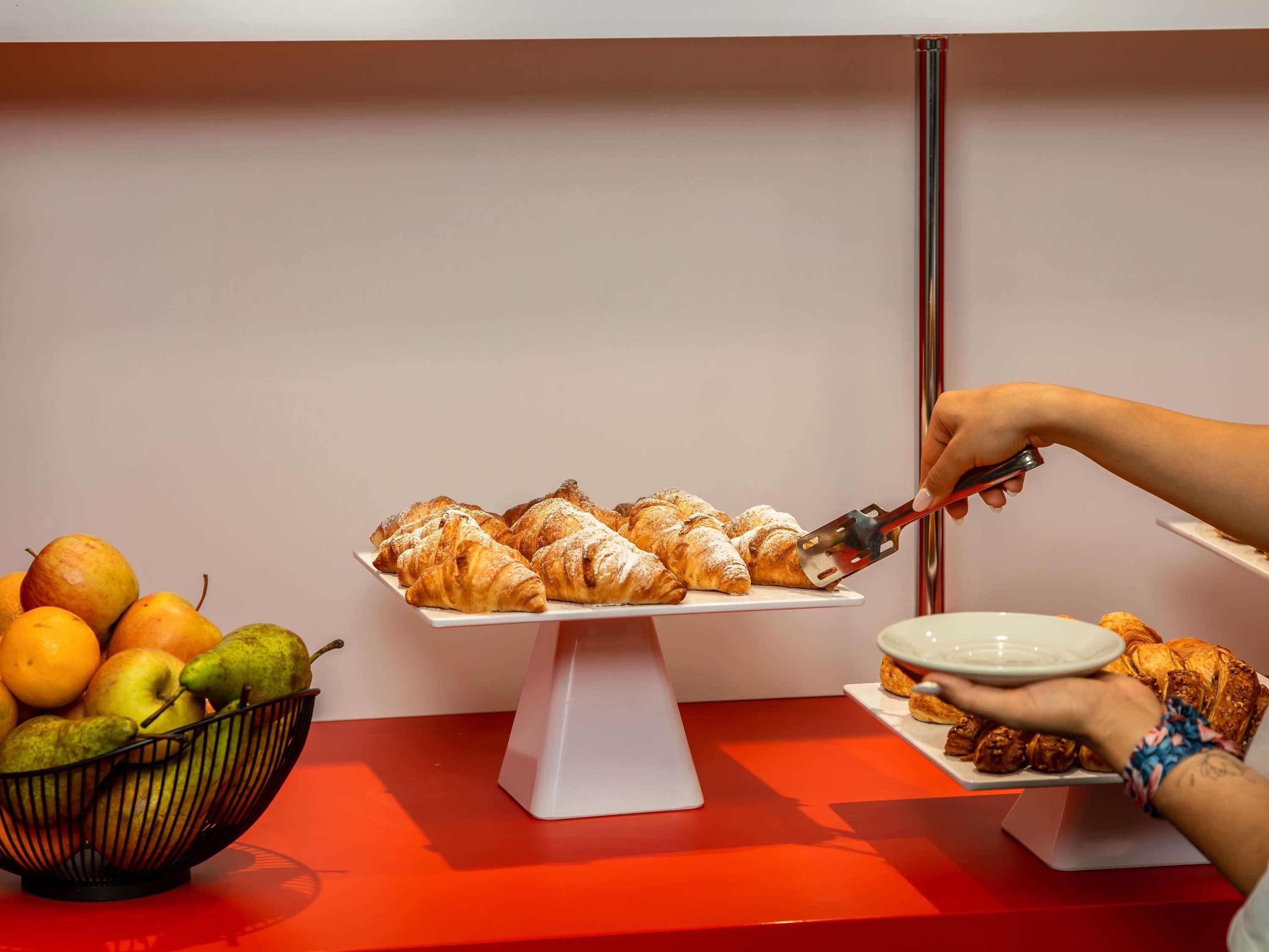 Une table de buffet avec des pâtisseries et un saladier de fruits.