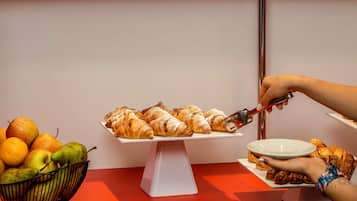 A buffet table with pastries and a bowl of fruit.