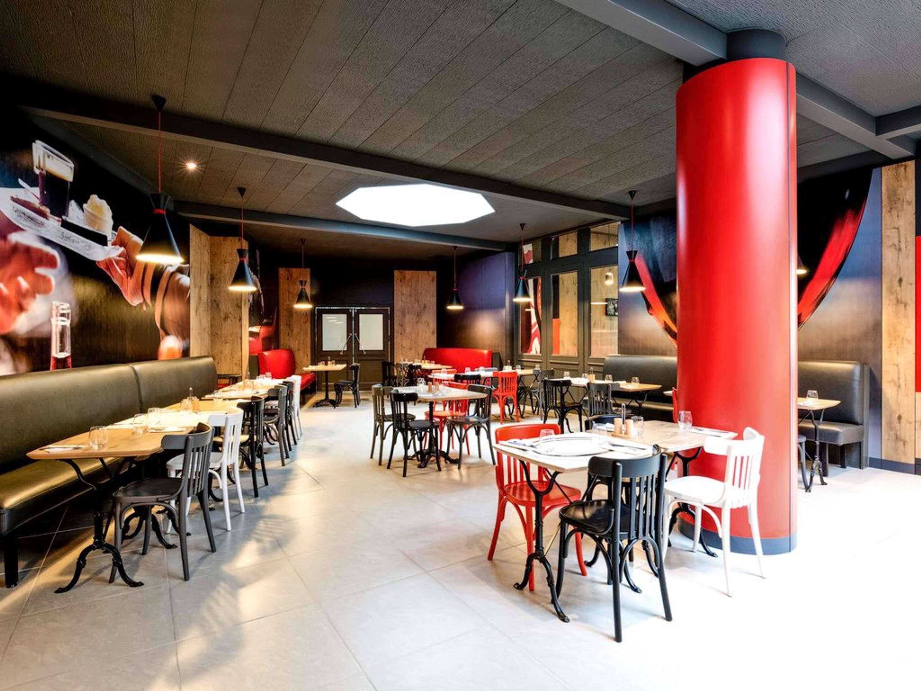 Een modern restaurantinterieur met zitjes, tafels en rode accenten.